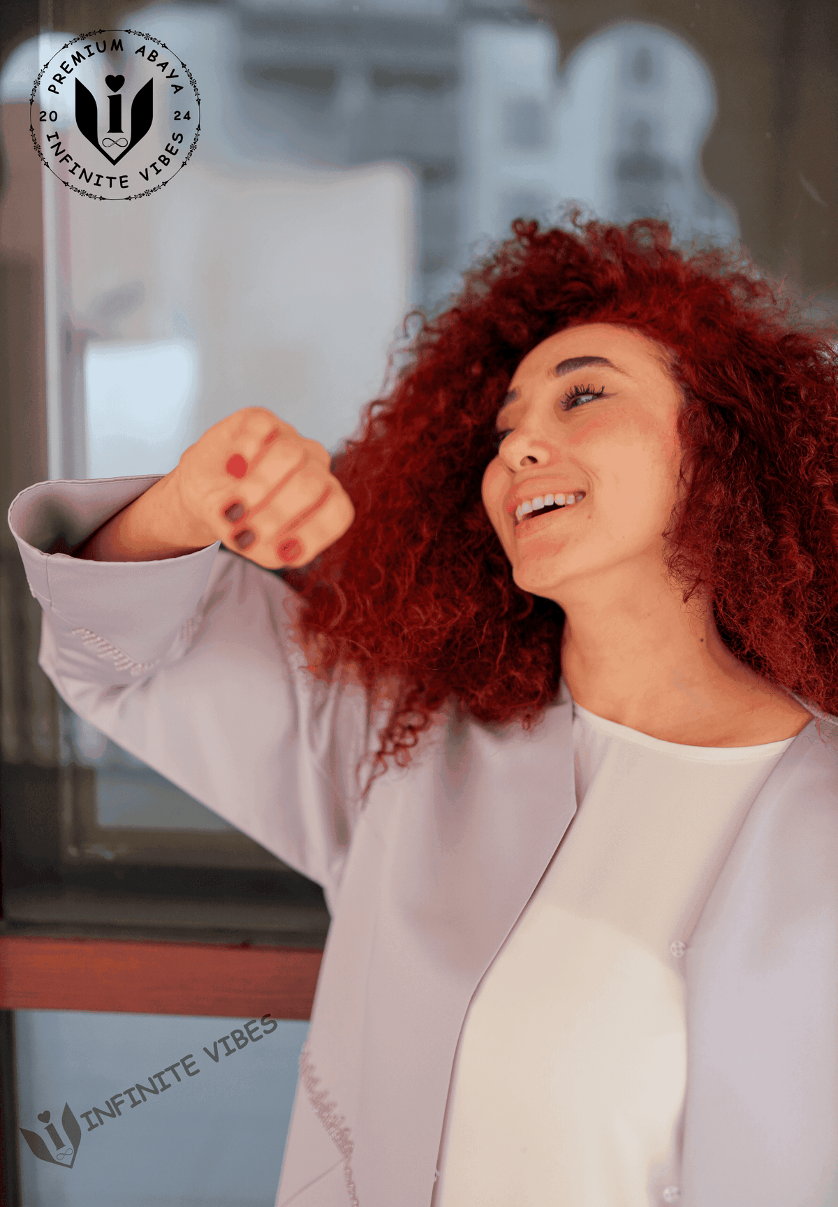 Smiling woman with curly red hair wearing a lavender designer abaya, modern modest fashion