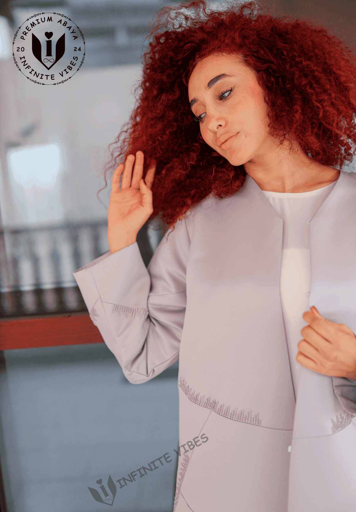 Woman with curly red hair wearing a light lavender designer abaya with stitched details