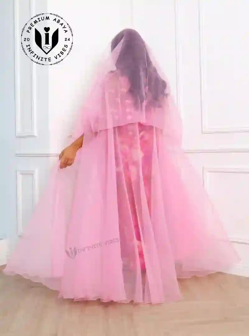 Woman modeling a flowing pink sheer designer abaya with veil in a modern interior.