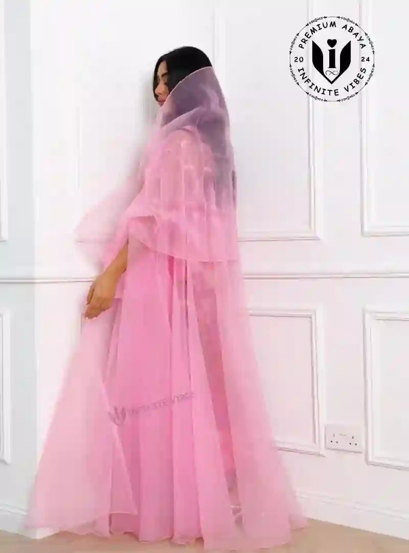 Woman wearing a sheer pink designer abaya, modest fashion, standing indoors