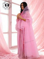 Woman wearing a sheer pink designer abaya with hood in a soft pink indoor setting