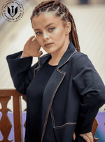 Woman with braided hair modeling a black designer abaya with beige contrast stitching.