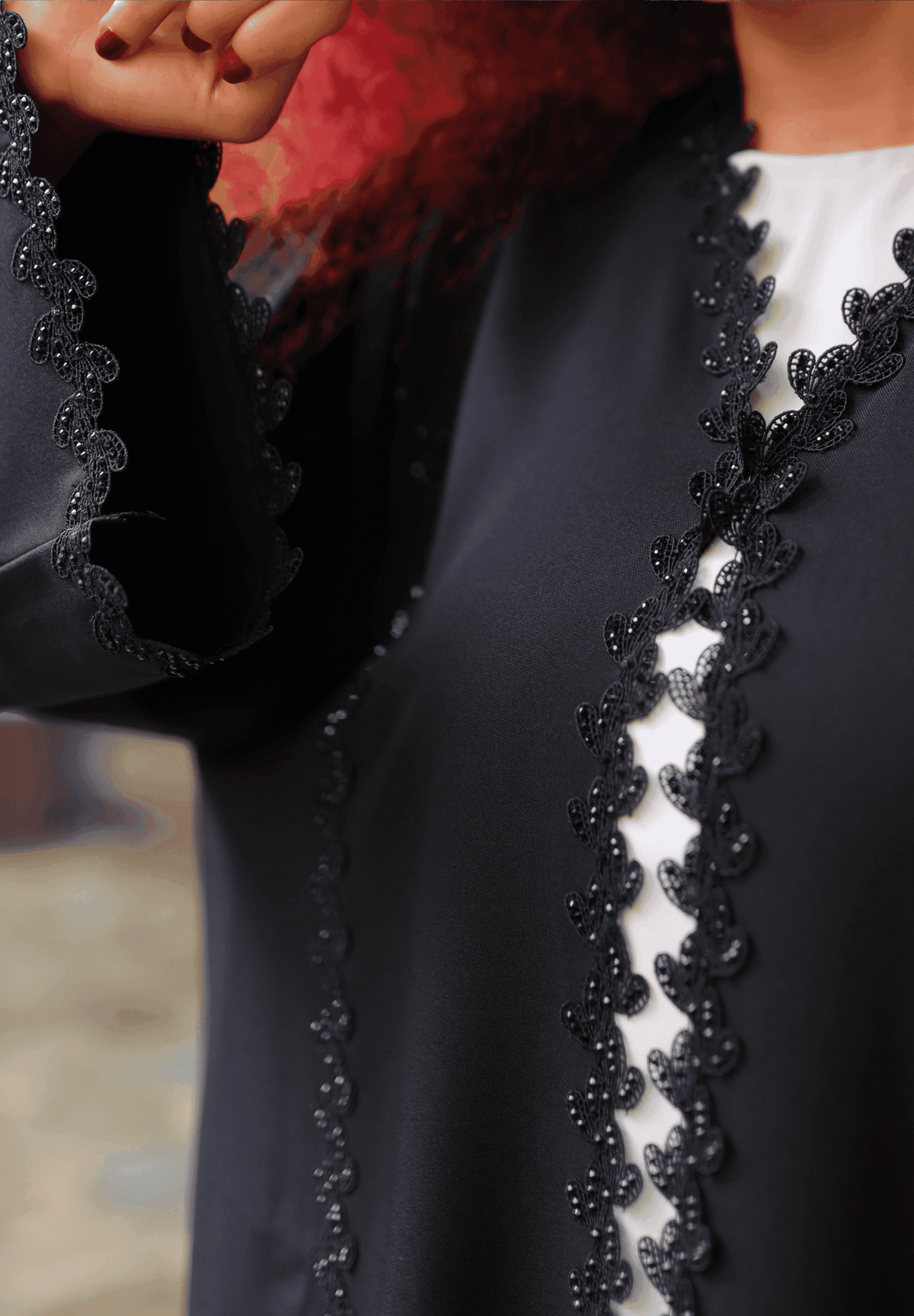 Close-up of a black designer abaya with intricate lace detailing on the front and sleeves