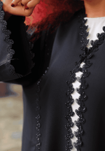 Close-up of a black designer abaya with intricate lace detailing on the front and sleeves