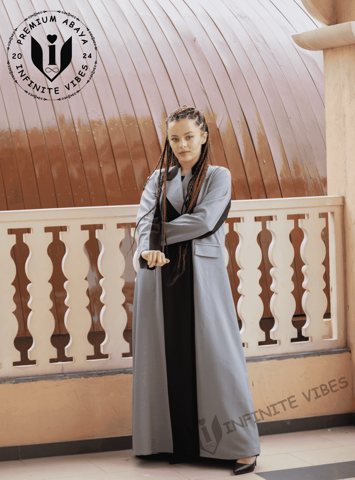 Woman wearing a stylish grey designer abaya with black accents on a balcony