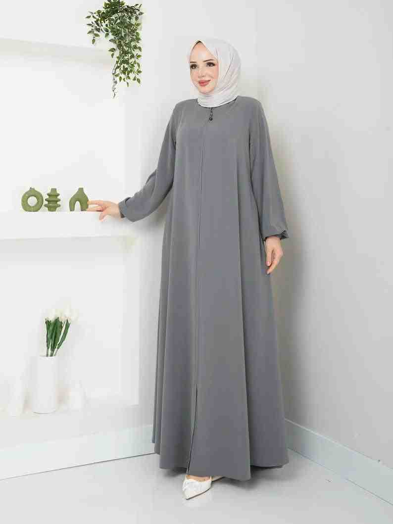 Woman wearing a grey modest abaya with white hijab in a minimalist room