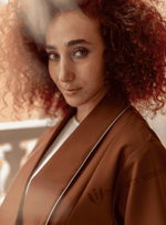 Woman with curly hair wearing a brown designer abaya, luxury modest fashion in UAE