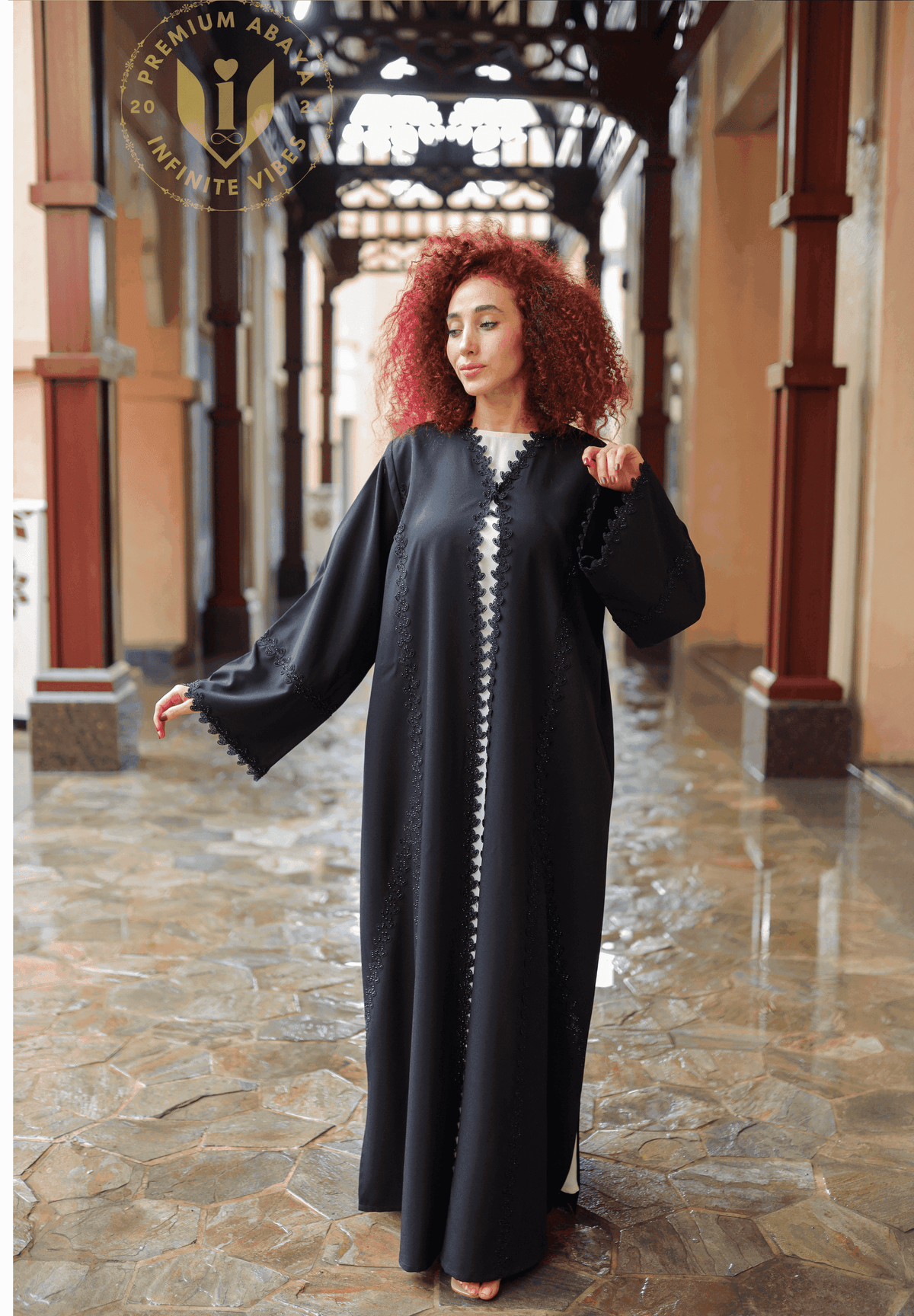 Woman in designer black abaya with lace details in elegant Middle Eastern corridor