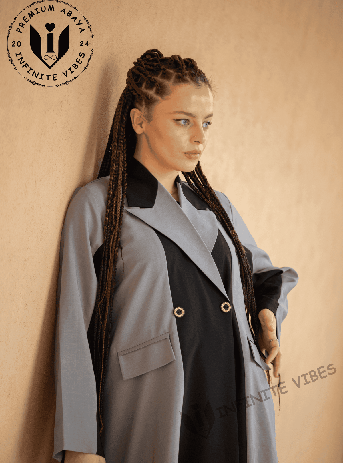 Woman in designer abaya with braids, wearing a light grey and black modest fashion outfit.