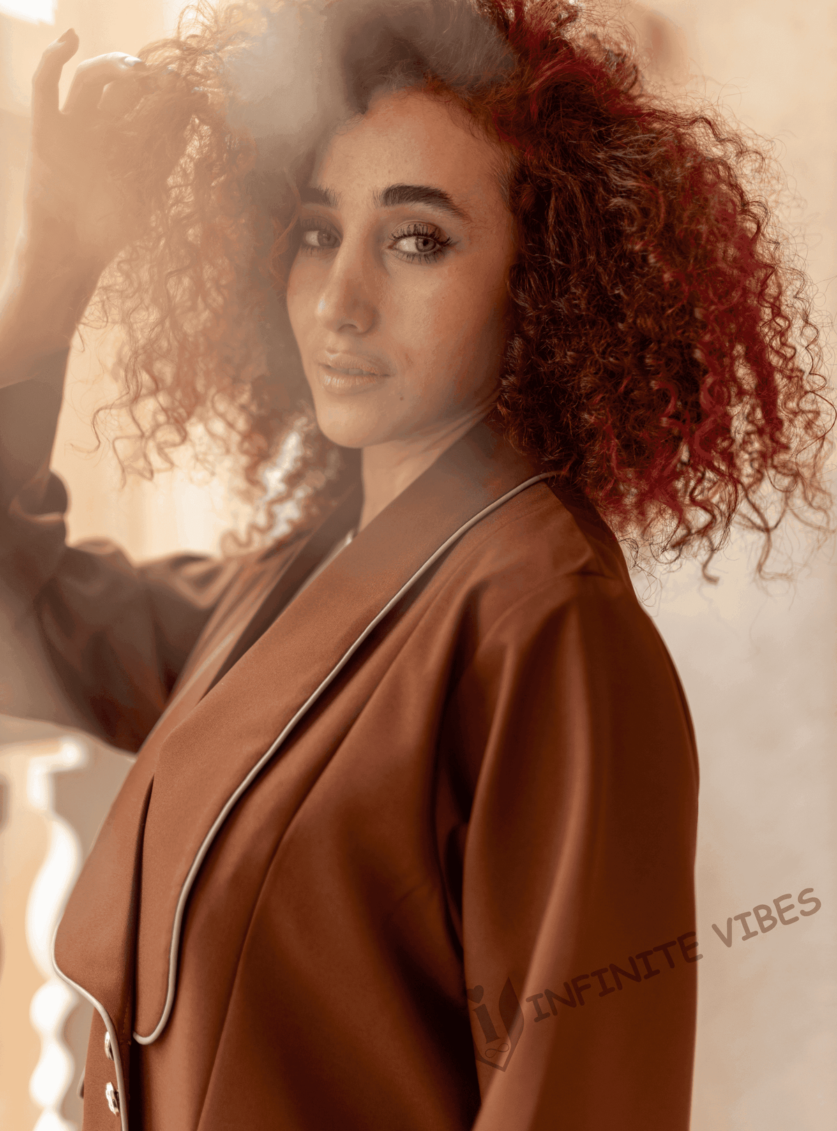Woman wearing a brown designer abaya with white trim, posing indoors in soft light.