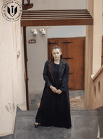 Woman in a modern black designer abaya with contrast trim, standing on outdoor stairs