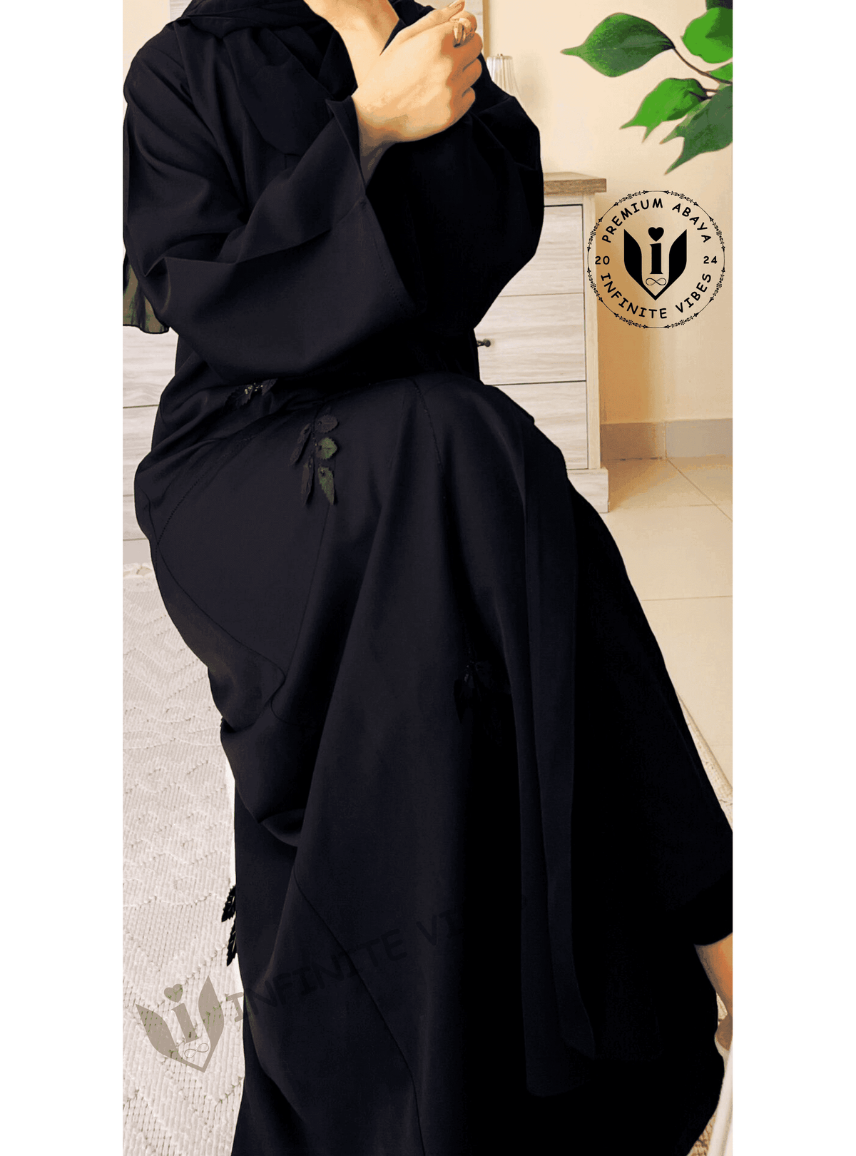 Elegant black abaya with subtle leaf embroidery, worn indoors on a light modern background.