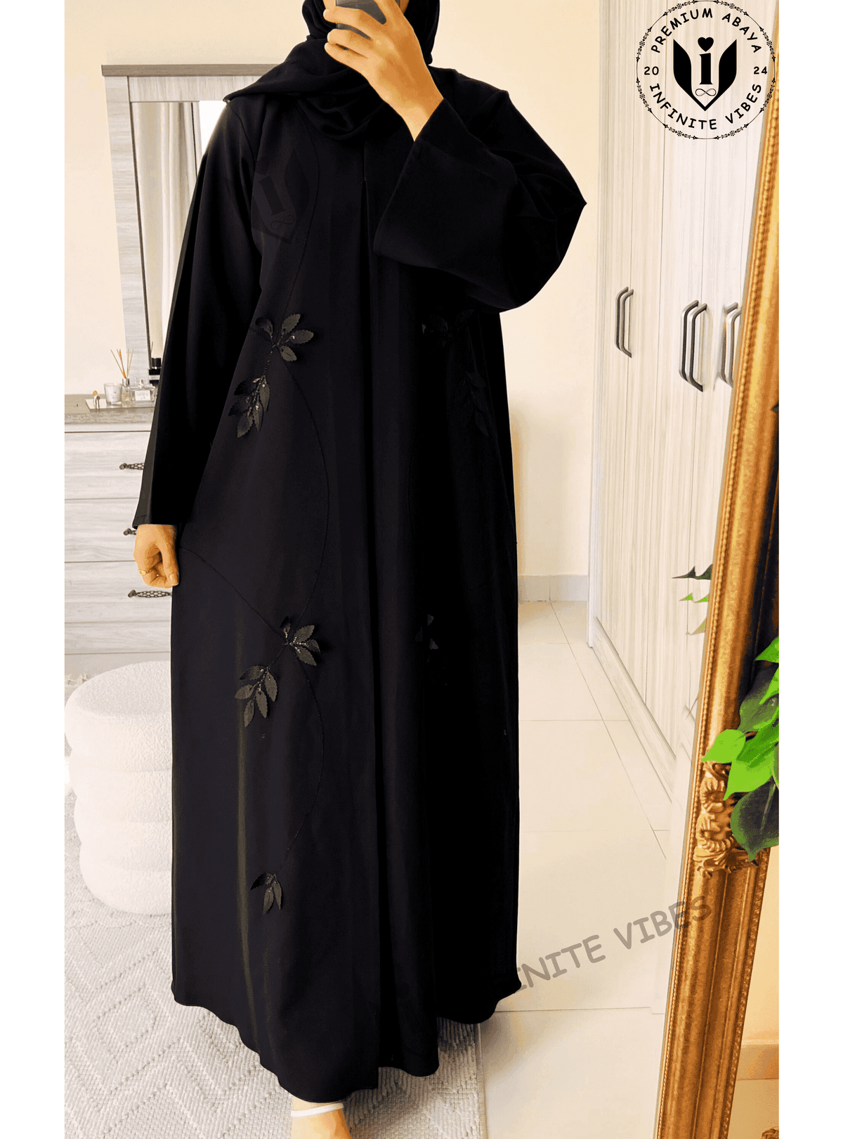 Black designer abaya with subtle leaf appliqué, loose fit, modest fashion style, indoors