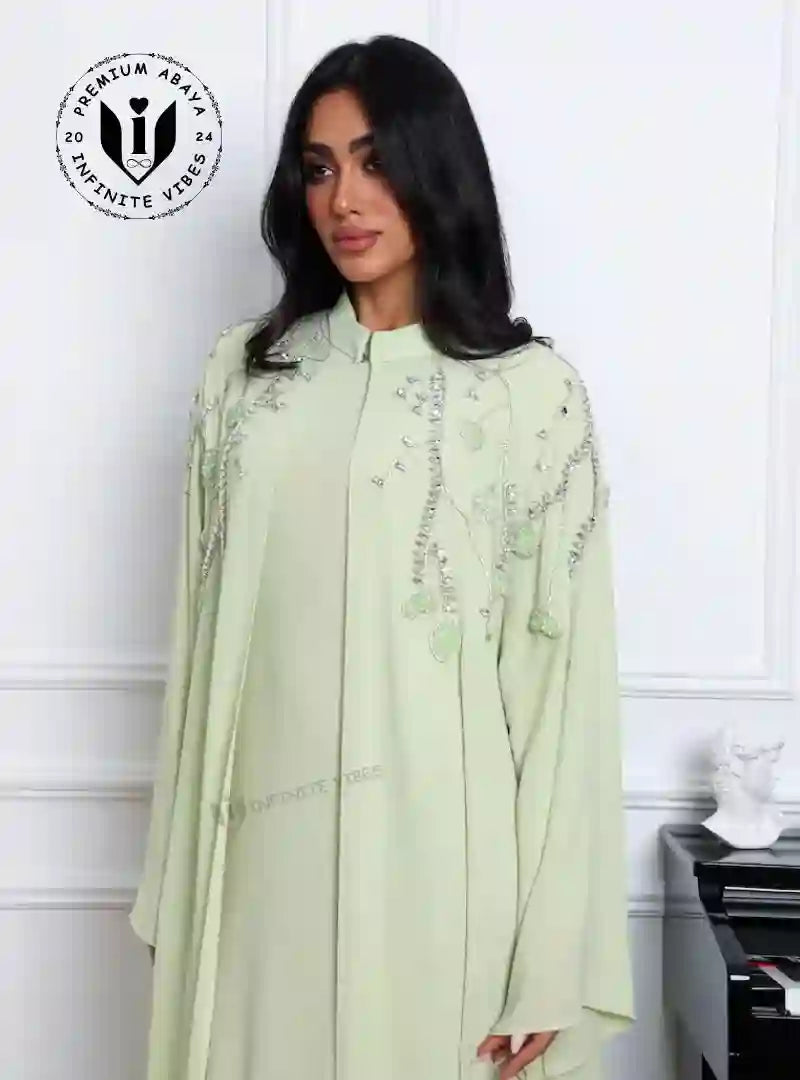 Woman wearing pistachio green embroidered abaya set, modest fashion, UAE style