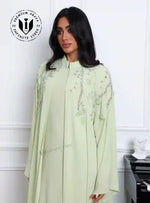 Woman wearing pistachio green embroidered abaya set, modest fashion, UAE style
