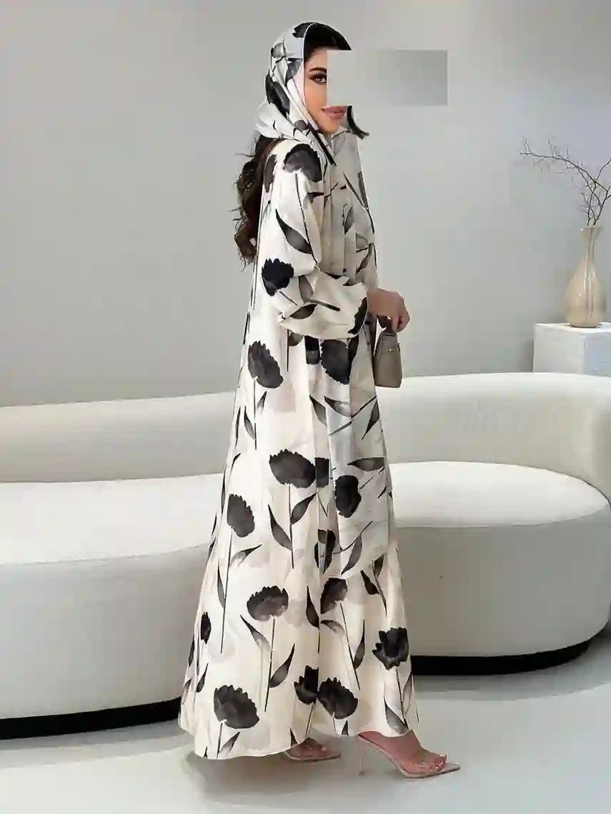 Woman wearing luxury floral abaya with hood, holding a purse in modern living room