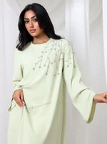 Light green chiffon abaya with crystal embellishments on shoulder, modest UAE fashion.