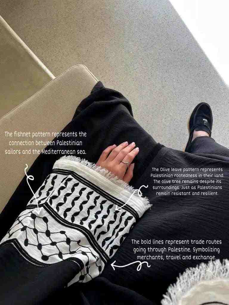 Woman wearing a black designer abaya with embroidered sleeve featuring Palestinian-inspired patterns and detailed symbolic motifs.