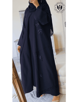 Woman wearing a black designer abaya with subtle leaf embroidery, modest fashion in UAE