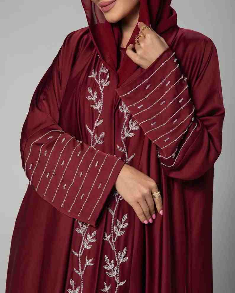 Woman wearing maroon embroidered abaya with leaf and striped patterns, modest fashion