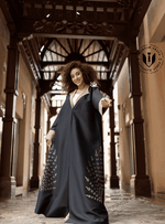 Woman wearing a luxury navy blue designer abaya with gold accents in an ornate hallway