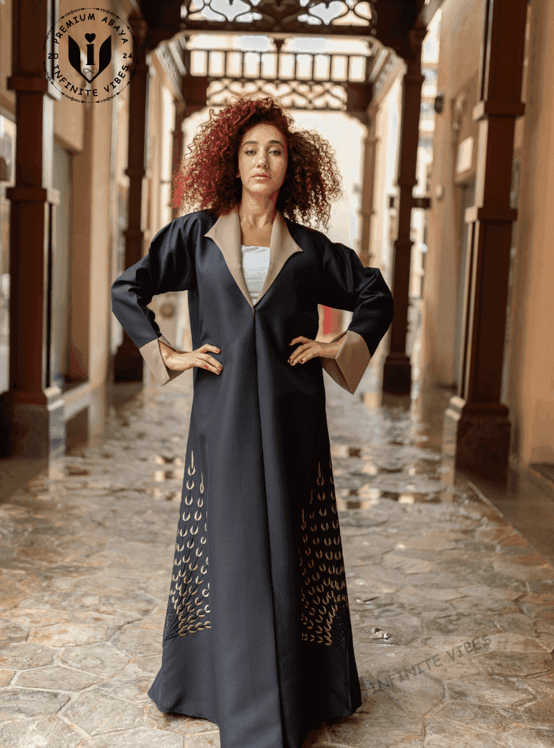 Woman wearing a designer black abaya with gold details in a traditional Middle Eastern corridor