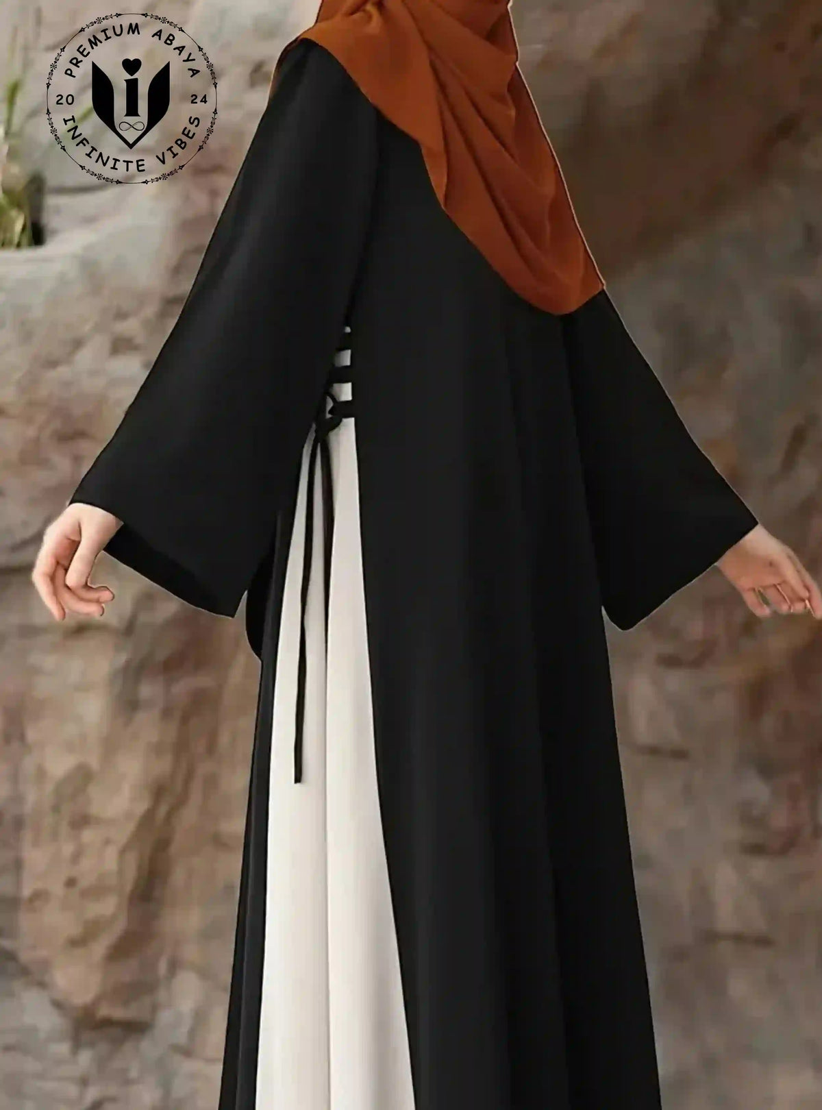 Elegant black abaya with white insert and tie detail, worn with rust hijab, modern modest fashion