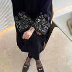 Black abaya with white floral embroidery on sleeves, modest fashion, UAE style.