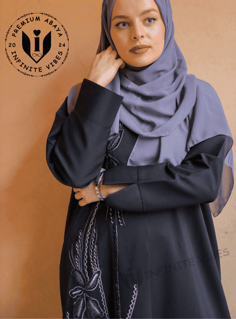 Woman wearing a black handwork abaya with embroidered floral details and grey hijab.