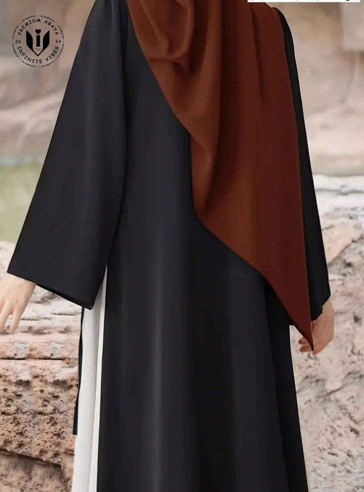 Modern black abaya with side lace-up detail, worn with brown hijab, outdoors in UAE