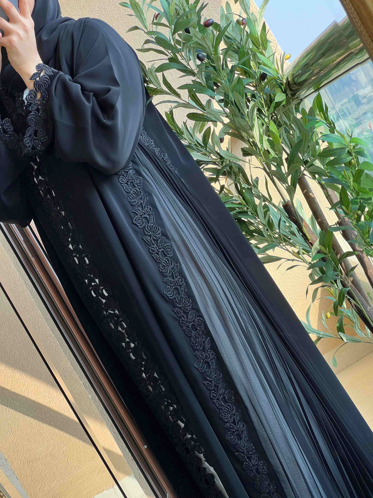Elegant black abaya with lace and embroidery details, modest fashion in natural light