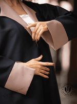 Woman wearing a black abaya with taupe cuffs and collar, showcasing modest fashion.