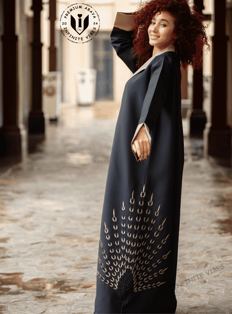 Woman wearing a black embroidered abaya with gold detailing in an outdoor corridor setting.