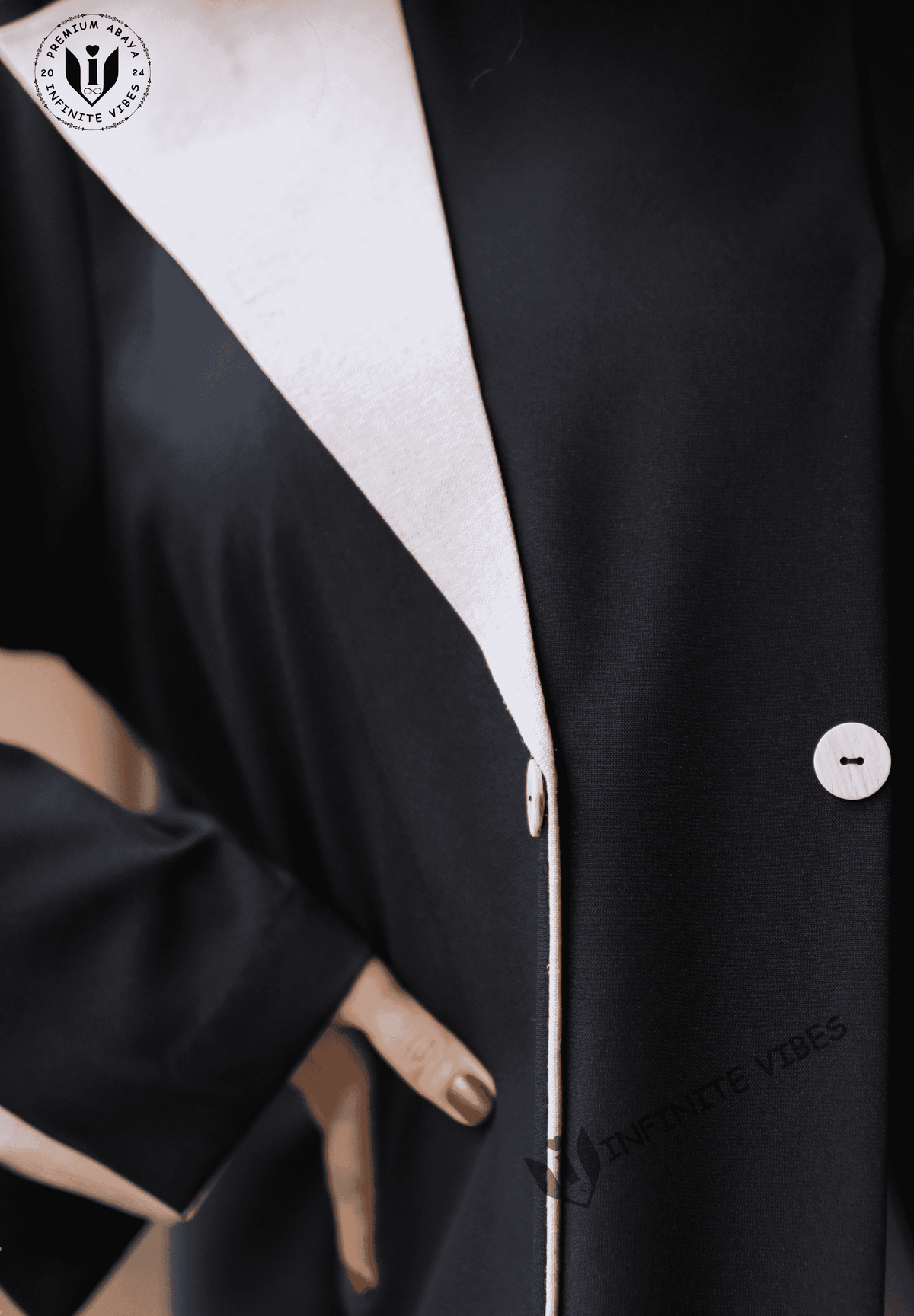 Close-up of a black abaya with white trim and buttons, showcasing modest fashion style