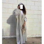 Elegant woman wearing embroidered open abaya with maxi dress and headband, holding handbag