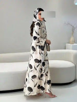Woman wearing a long-sleeve printed floral abaya with headscarf in modern living room