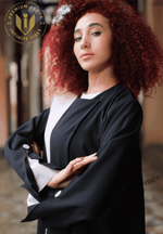Woman in elegant black designer abaya with white details, posing confidently indoors