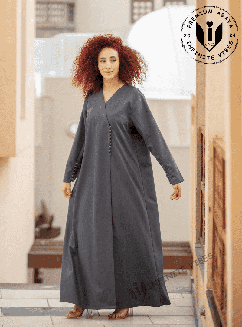 Woman wearing a charcoal grey designer abaya with button details, standing outdoors in UAE