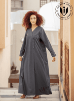 Woman wearing a charcoal grey designer abaya with button details, standing outdoors in UAE