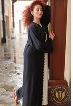 Woman in a black designer abaya with lace trim standing in an elegant corridor