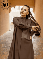 Woman wearing a modern brown designer abaya with zipper detail in an outdoor setting