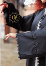 Black designer abaya with intricate beaded trim and flared sleeves, outdoor setting