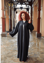 Woman in designer black abaya with lace details in elegant Middle Eastern corridor