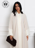 Elegant_beige_abaya_for_women_with_white_satin_details_and_black_clutch_