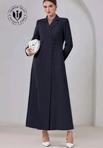 Modern double-breasted black abaya with lapel collar, worn with white heels and clutch.