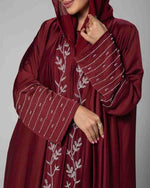 Woman wearing maroon embroidered abaya with leaf and striped patterns, modest fashion