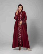 Woman wearing maroon embroidered abaya with hood, silver heels, studio background
