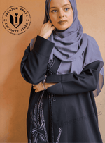 Woman wearing a black handwork abaya with embroidered floral details and grey hijab.