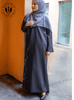 Woman in elegant black handwork abaya with embroidered details and grey hijab