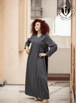Woman wearing a dark grey buttoned abaya with long sleeves in a modern indoor setting